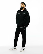 Black relaxed fit French terry hoodie with white Psycho Bunny text and three circular bunny skull logos on chest, paired with Mens Nathaniel Sweatpant featuring a white circular bunny skull logo on left thigh.