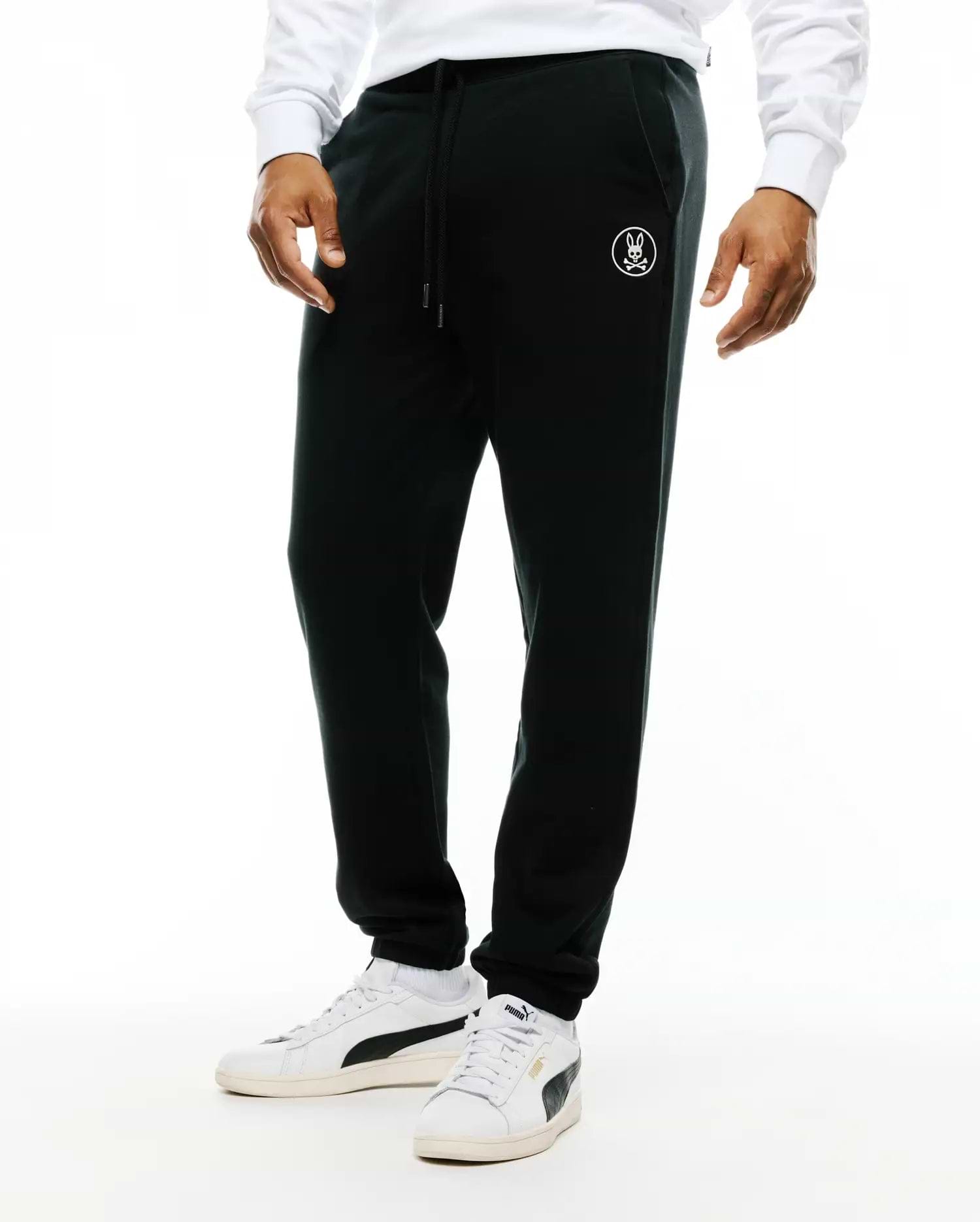 Mens Nathaniel Sweatpant, black relaxed fit french terry sweatpants with a drawstring waist, ribbed cuffs, and a small white embroidered Psycho Bunny skull logo on the left thigh.