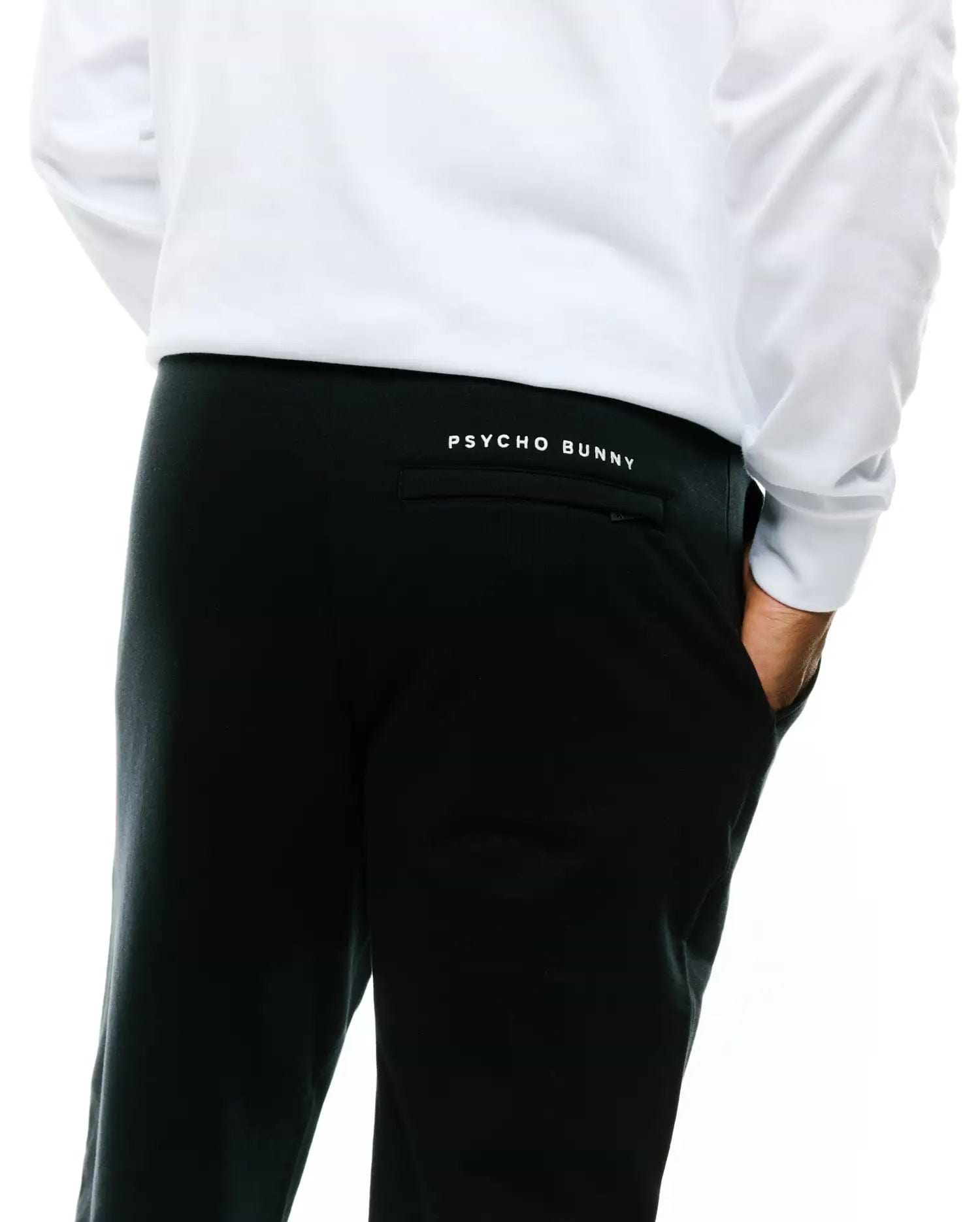 Mens Nathaniel Sweatpant, black relaxed fit French terry, featuring a small white embroidered Psycho Bunny text logo above the back right pocket.