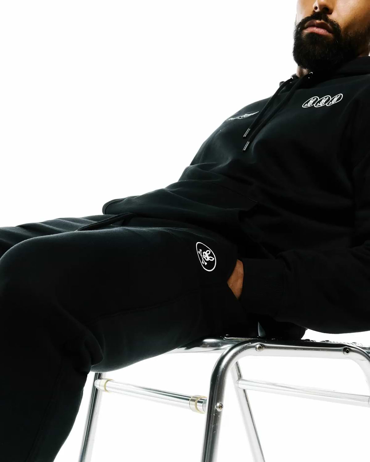 Black French terry hoodie with three small white outlined bunny skull logos on the chest and matching Mens Nathaniel Sweatpant with a white bunny skull logo on the left thigh, featuring a relaxed fit.