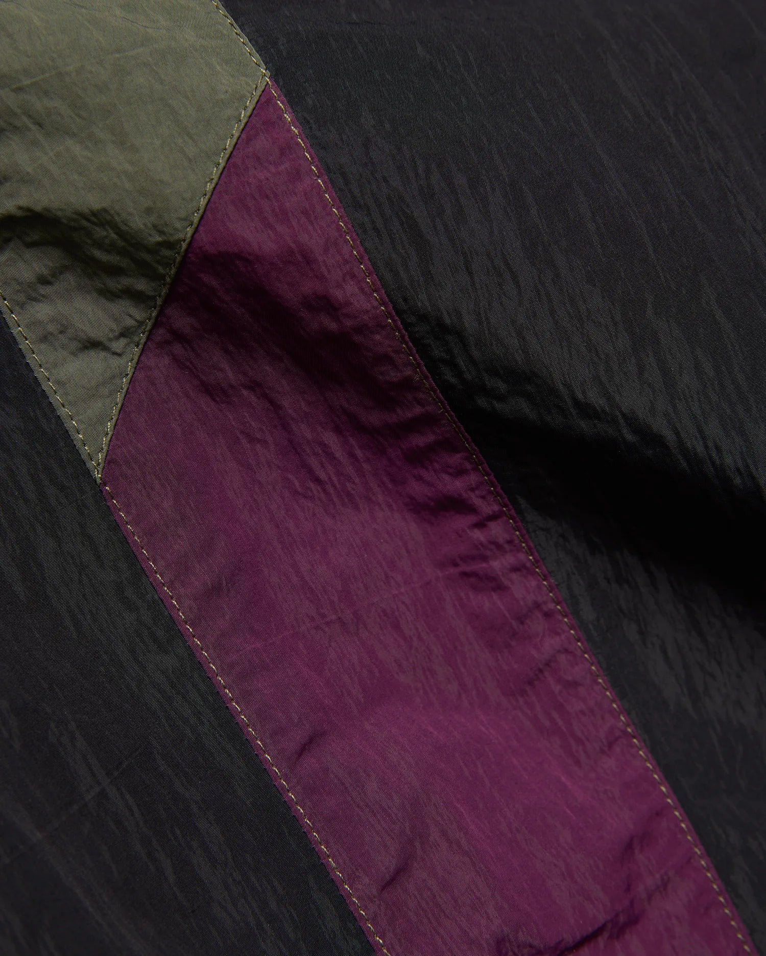 Mens Alder Nylon Colorblock Pant featuring crinkled black nylon with olive green and deep purple colorblock panels, accented by visible light stitching.