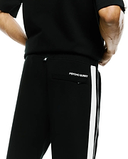 Mens Ceano Track Pant, black smooth knit with a white side stripe, featuring a white Psycho Bunny skull tag on the back waist and embroidered PSYCHO BUNNY text above the back pocket. (3)