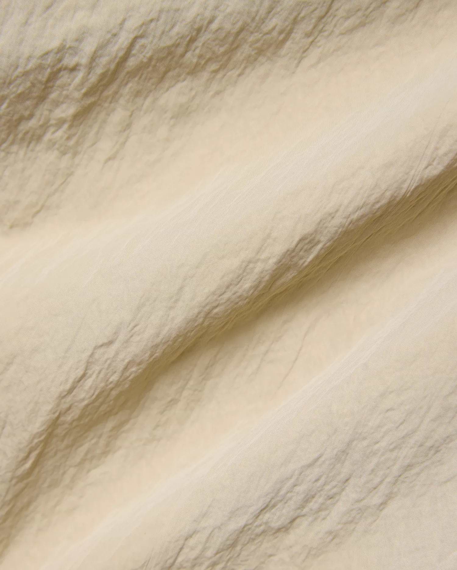 Mens Alder Nylon Pant in a sophisticated light beige hue, showcasing its premium, subtly textured and crinkled nylon fabric with a refined, fine weave, ideal for refined streetwear.