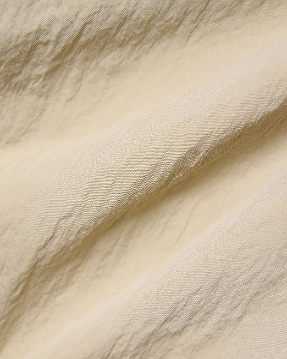 Mens Alder Nylon Pant in a sophisticated light beige hue, showcasing its premium, subtly textured and crinkled nylon fabric with a refined, fine weave, ideal for refined streetwear.
