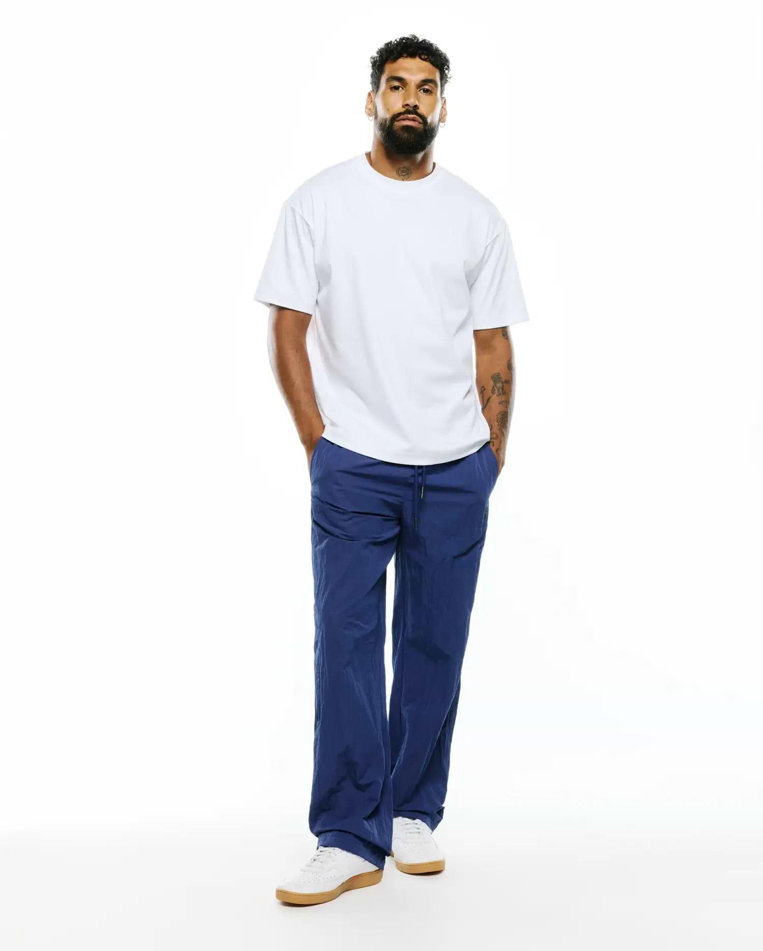Relaxed fit white jersey t-shirt paired with MENS ALDER NYLON PANT in deep blue, featuring a crinkled texture, drawstring waist, and a comfortable, refined streetwear aesthetic. (4)