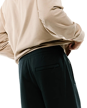 Dark charcoal Mens Terrence Brushed Fleece Sweatpant featuring a relaxed fit, elastic waistband, side pockets, and a subtle zippered back pocket, paired with a beige long-sleeve top.