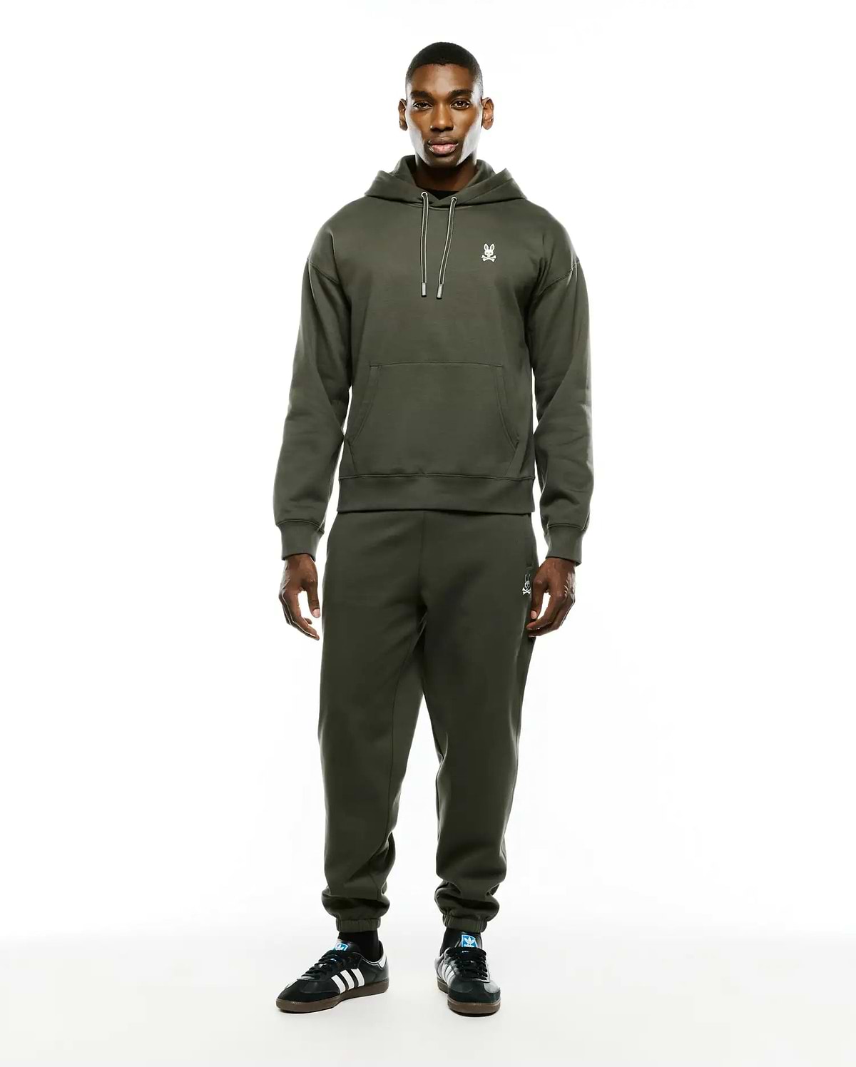 Olive green relaxed fit brushed fleece hoodie with white drawstring and embroidered Psycho Bunny skull chest logo. Paired with Mens Terrence Brushed Fleece Sweatpant, featuring an embroidered bunny skull thigh logo.
