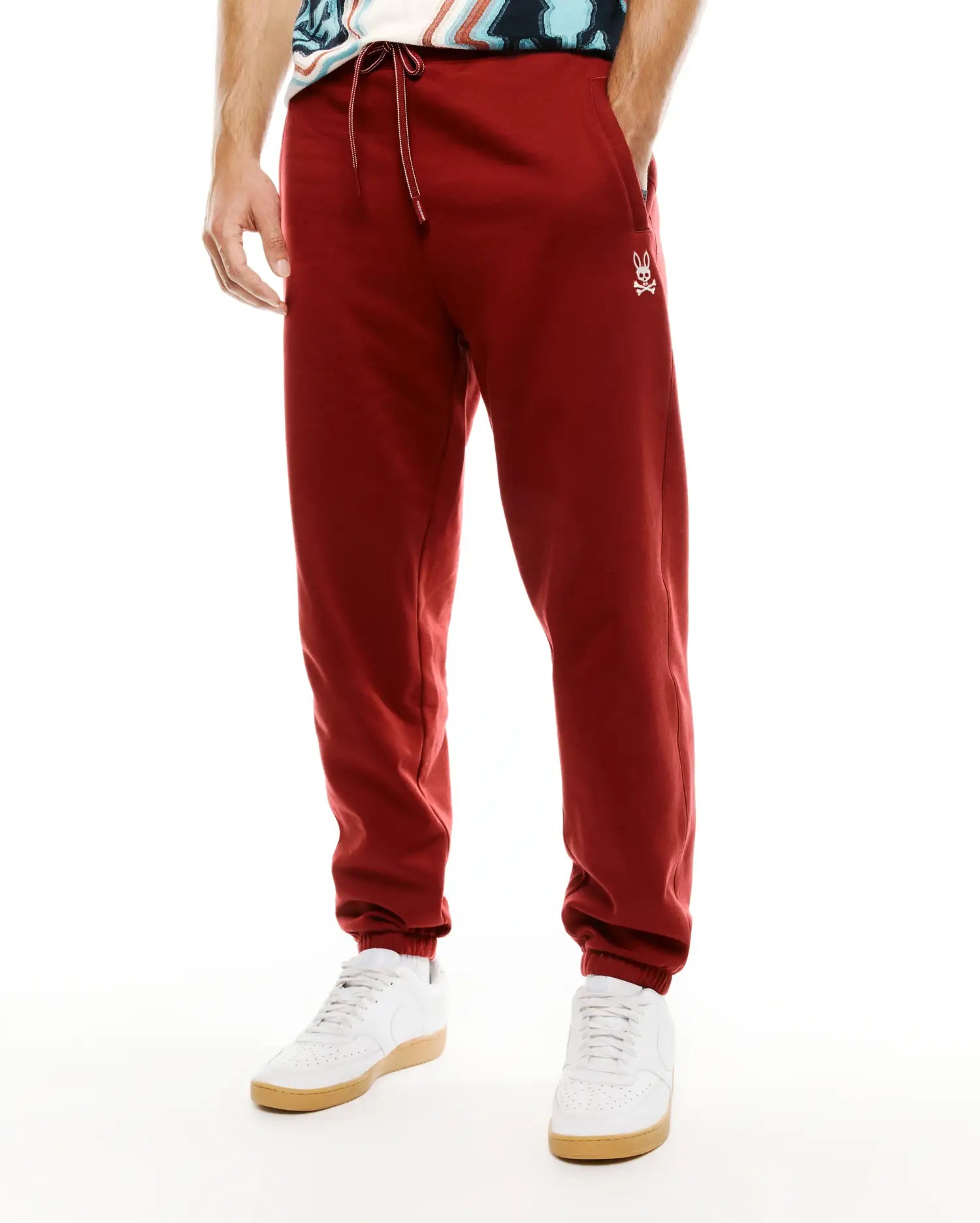 Mens Terrence Brushed Fleece Jogger in deep red, featuring a relaxed tapered fit, white drawstring, and small embroidered Psycho Bunny skull logo on the left thigh. (2)