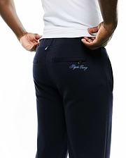 Men's Jacques Pique Track Pants in dark navy, featuring a relaxed fit, pique fabric, and a light blue embroidered Psycho Bunny script logo on the zippered back pocket, plus a small logo tag on the waistband. (3)