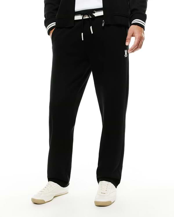 Men's Jacques Pique Track Pants in black, offering a relaxed fit with a white drawstring waist, subtle pique texture, and a small white embroidered Psycho Bunny skull logo on the right thigh. (2)