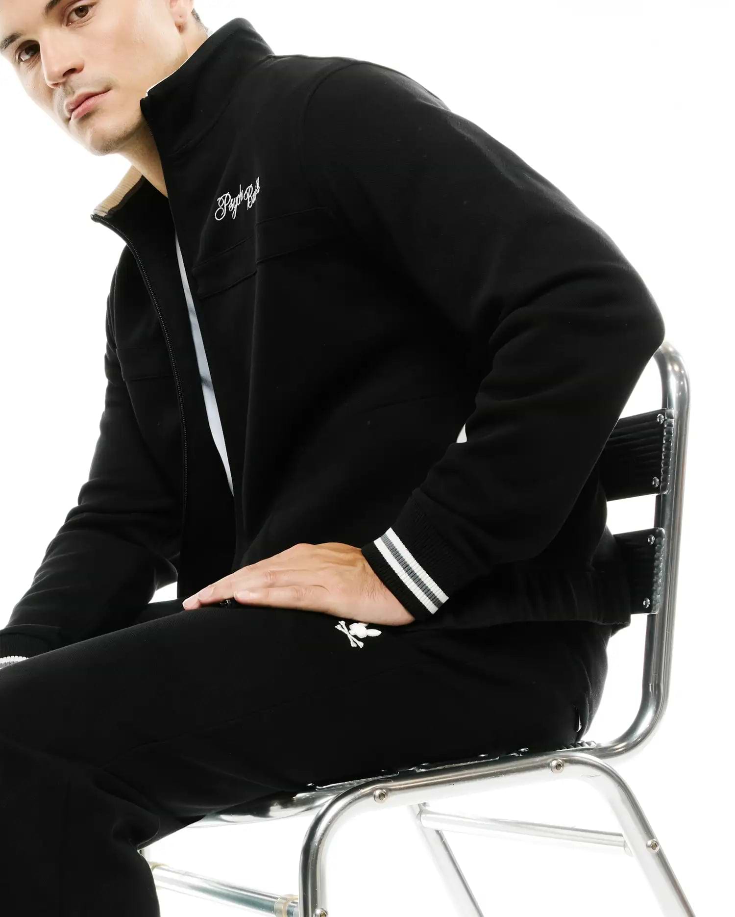 Black full-zip track jacket with cream collar lining, white embroidered script logo, striped cuffs, and matching Men's Jacques Pique Track Pants with white bunny skull logo. (4)