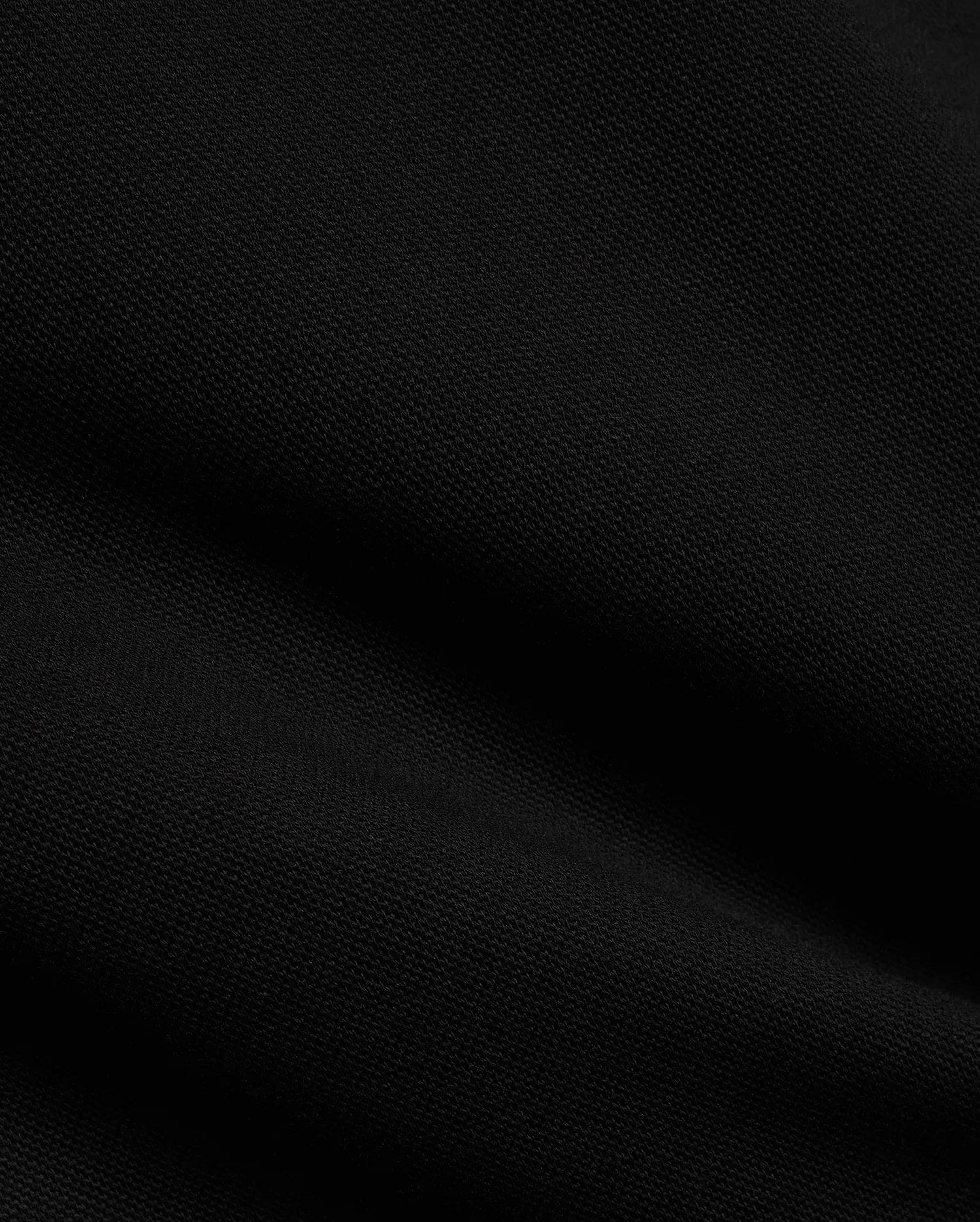 Men's Jacques Pique Track Pants in deep black, showcasing the refined, breathable pique knit fabric texture with subtle diagonal ribbing and soft folds, characteristic of premium Psycho Bunny streetwear. (6)