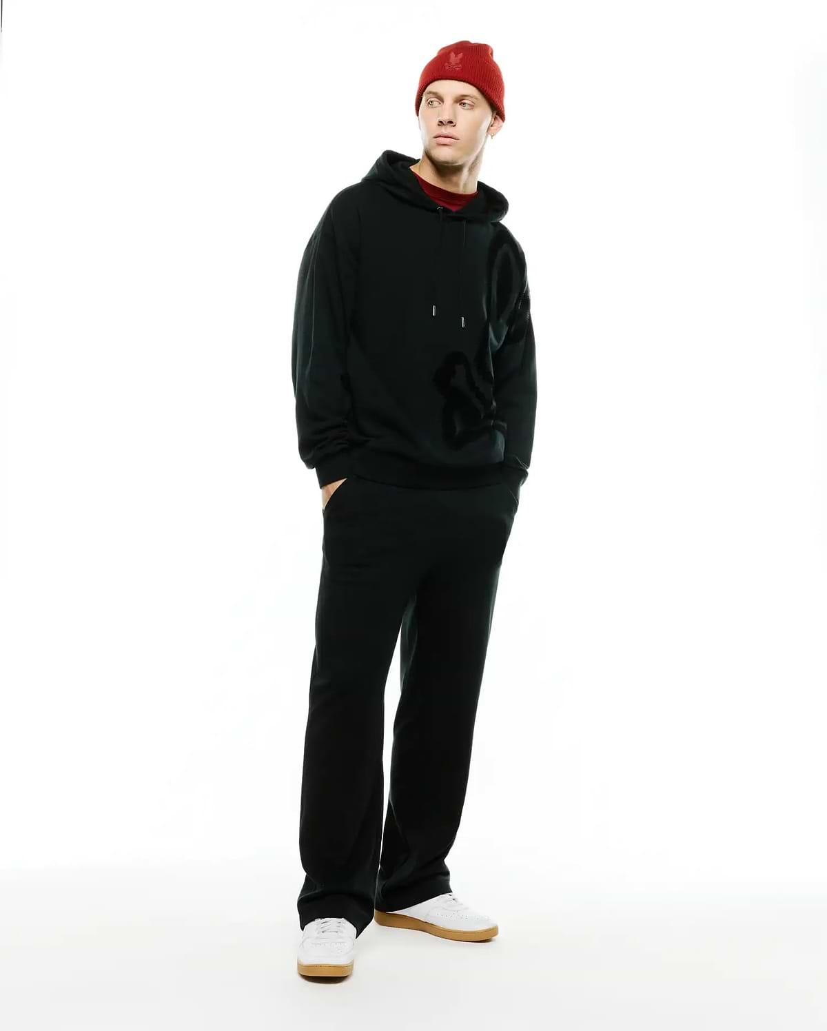 Black relaxed fit French terry hoodie with large tonal Psycho Bunny skull logo, paired with Men's Johan Straight-Leg Sweatpants and a red knit beanie featuring an embroidered bunny skull. (1)