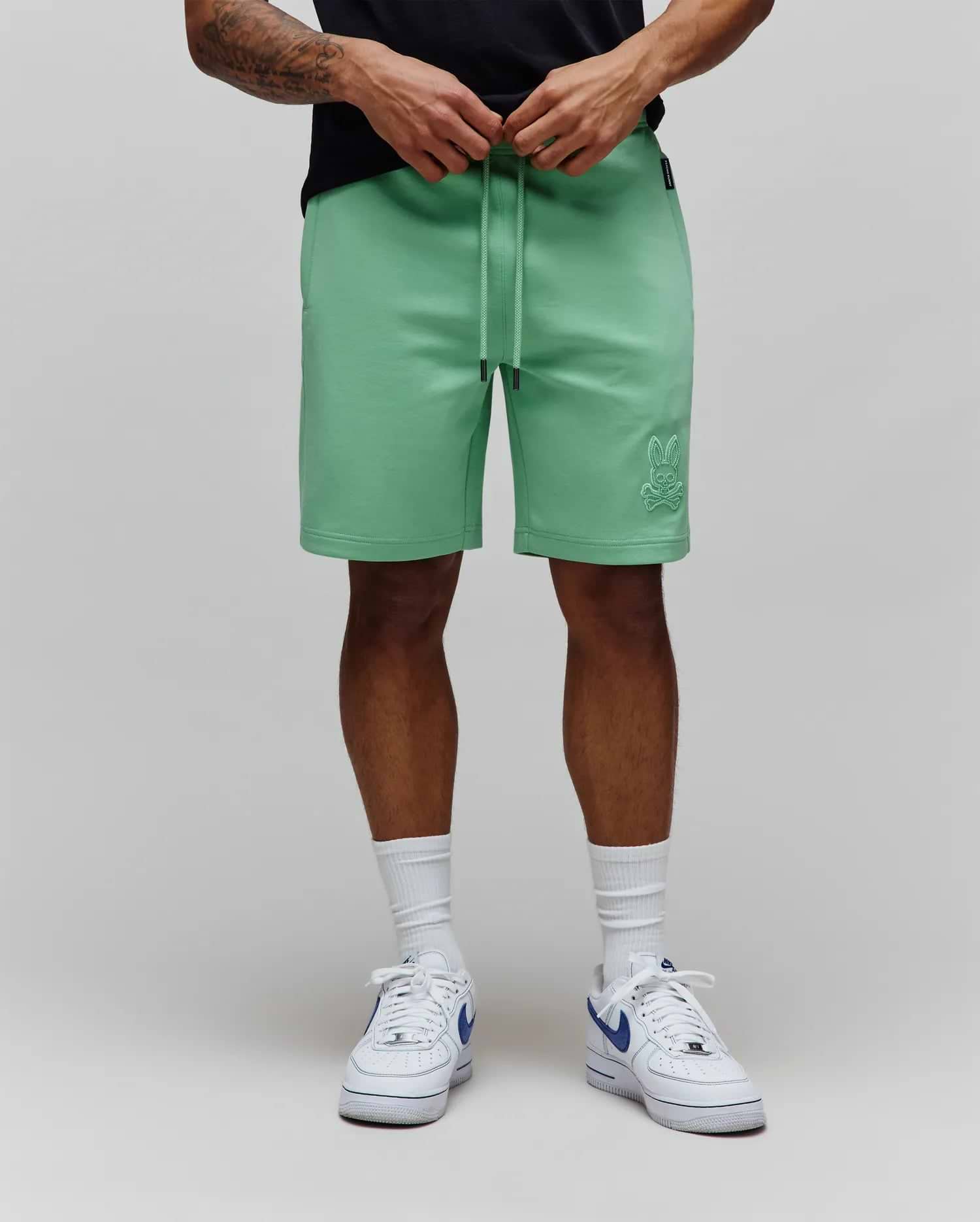 Mint Green Mens Barry Short in relaxed fit jersey fabric, featuring a drawstring waist with black tips and a tonal embroidered Psycho Bunny skull logo on the lower left leg.