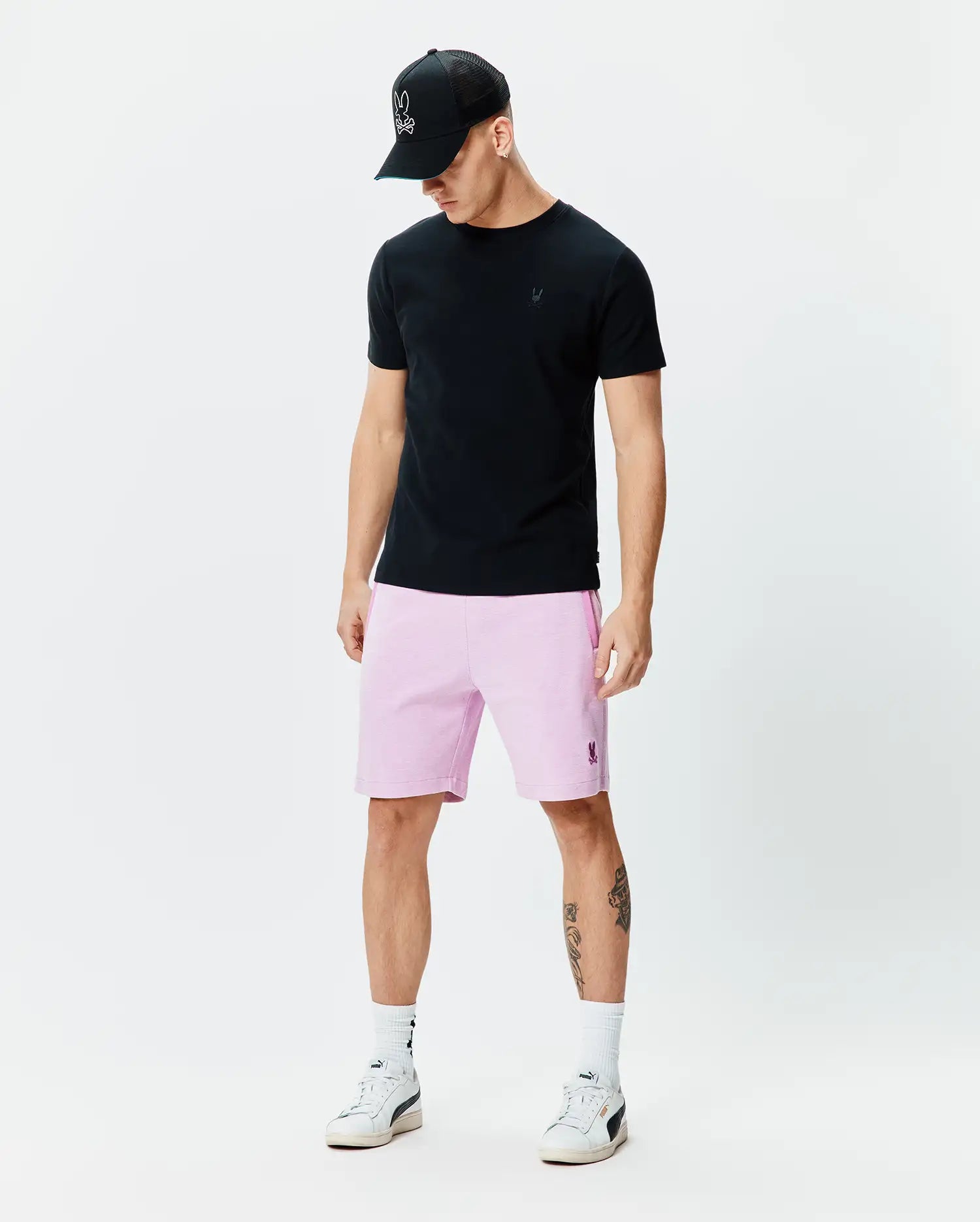 Black jersey t-shirt with tonal Psycho Bunny logo, pale pink Mens Keith Short 8 with embroidered logo, and black trucker cap with white embroidered Psycho Bunny skull.