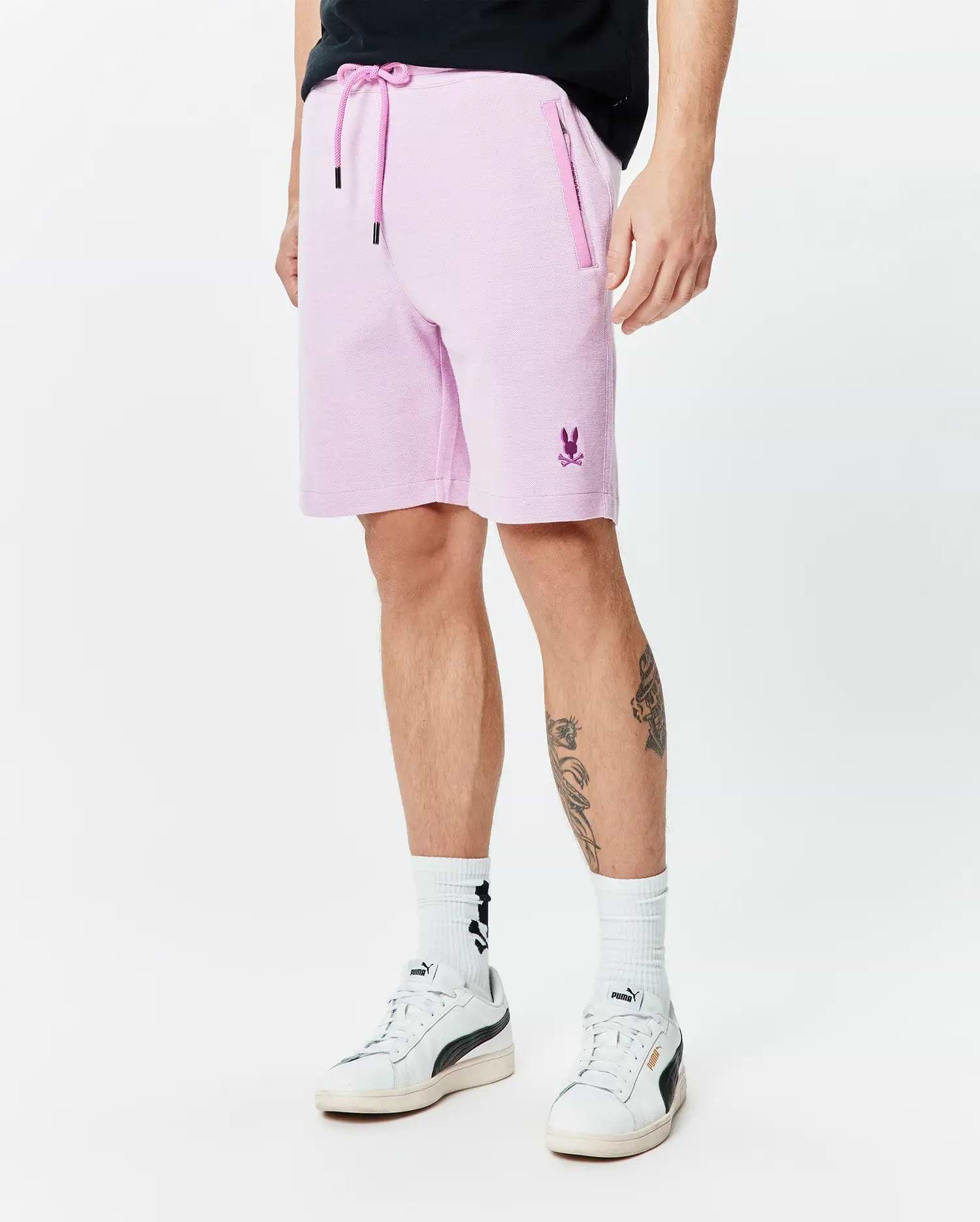 Mens Keith Short 8, light pink pique knit shorts with a classic fit, pink drawstring waist, zippered side pockets, and a small embroidered purple Psycho Bunny logo on the left leg.