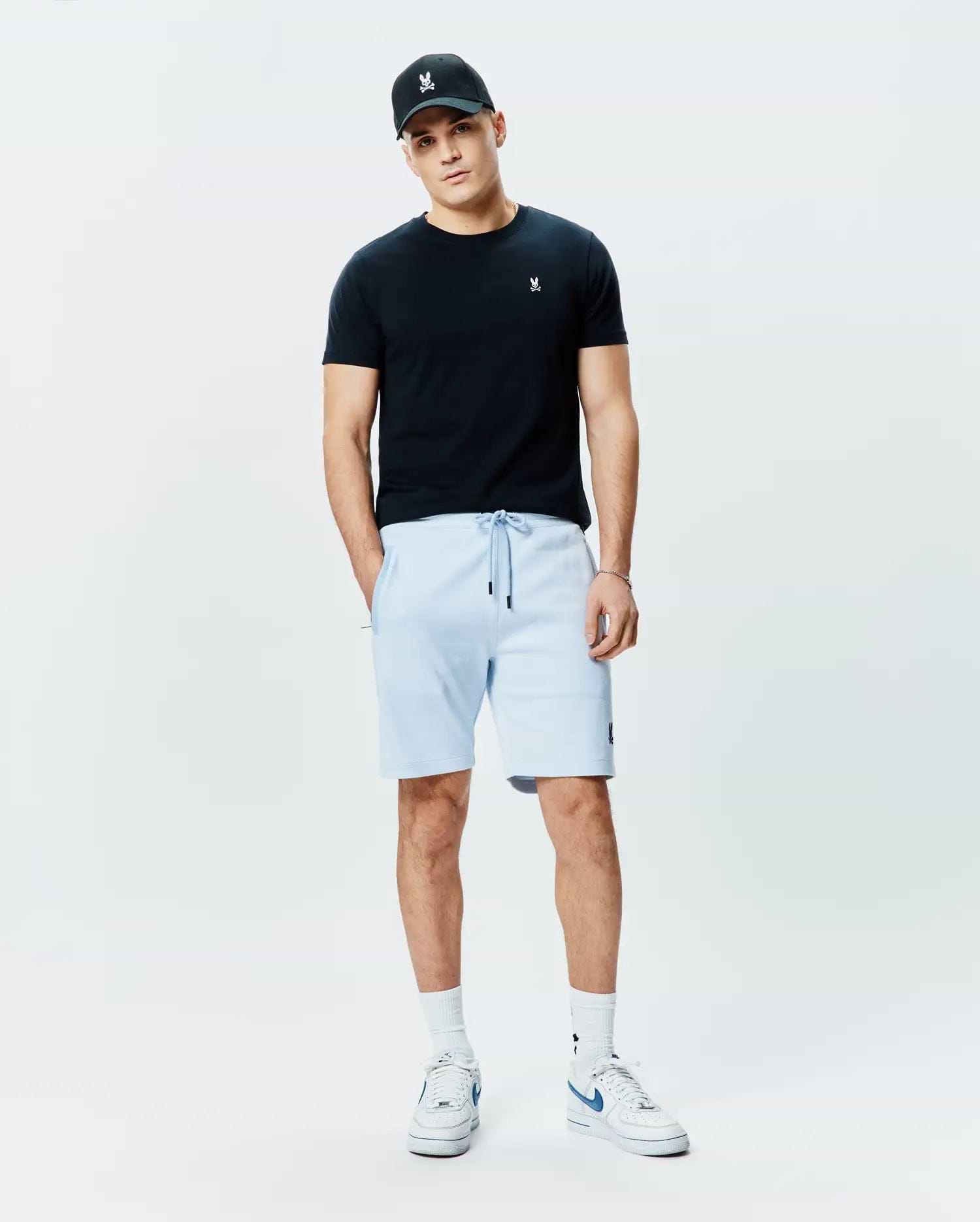 Black jersey t-shirt with white Psycho Bunny logo on chest, light blue Mens Keith Short 8 French terry shorts with black drawstrings and bunny logo on thigh, plus a black cap with white bunny skull.