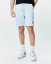 Mens Keith Short 8 light blue pique knit shorts, relaxed fit, featuring a drawstring waist with black tips, side pockets, and a small embroidered navy Psycho Bunny skull logo on the left leg.