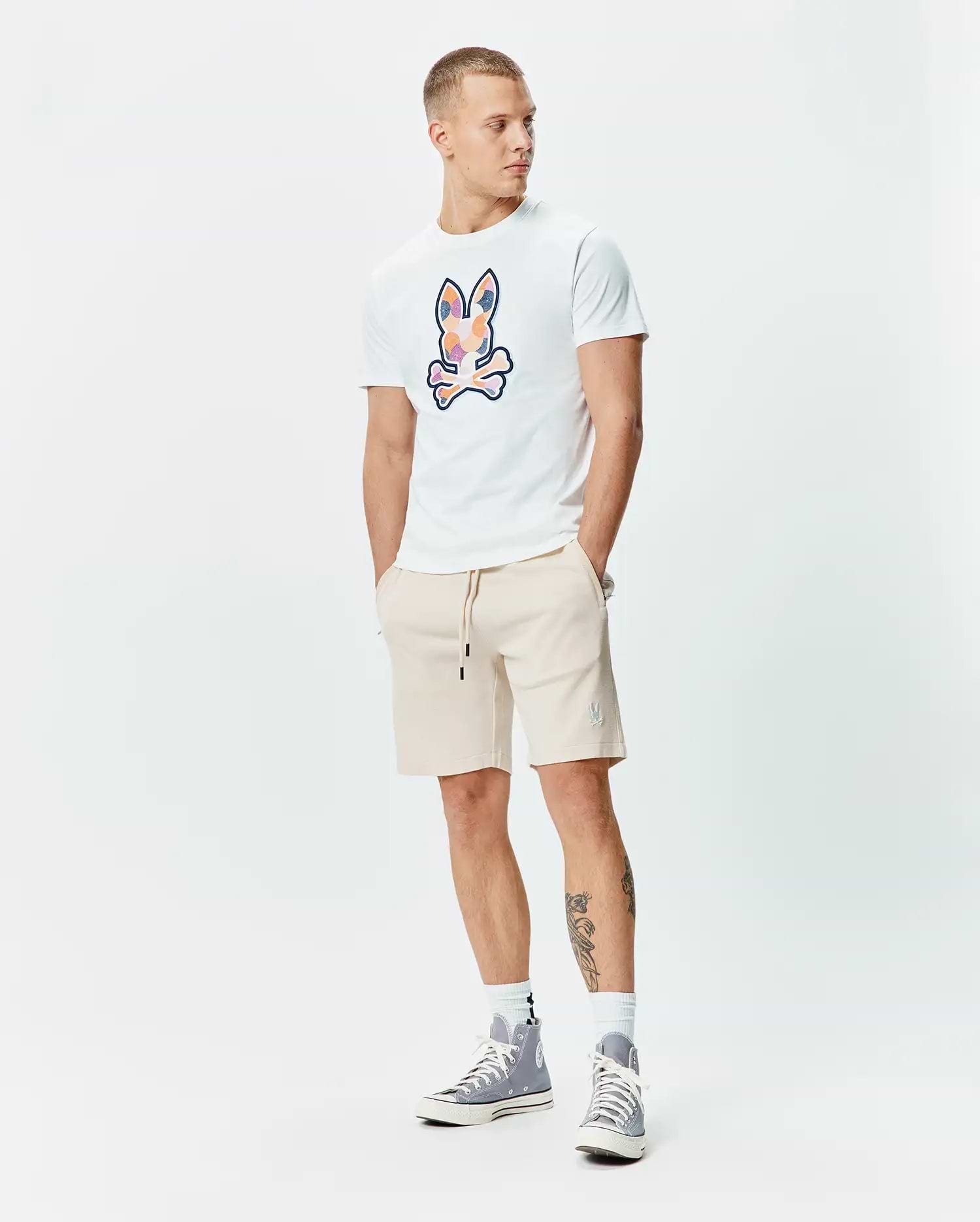 White classic fit jersey t-shirt with large multi-color graphic Psycho Bunny skull. Beige relaxed fit French terry Mens Keith Short 8 with small embroidered bunny logo and black drawstrings.