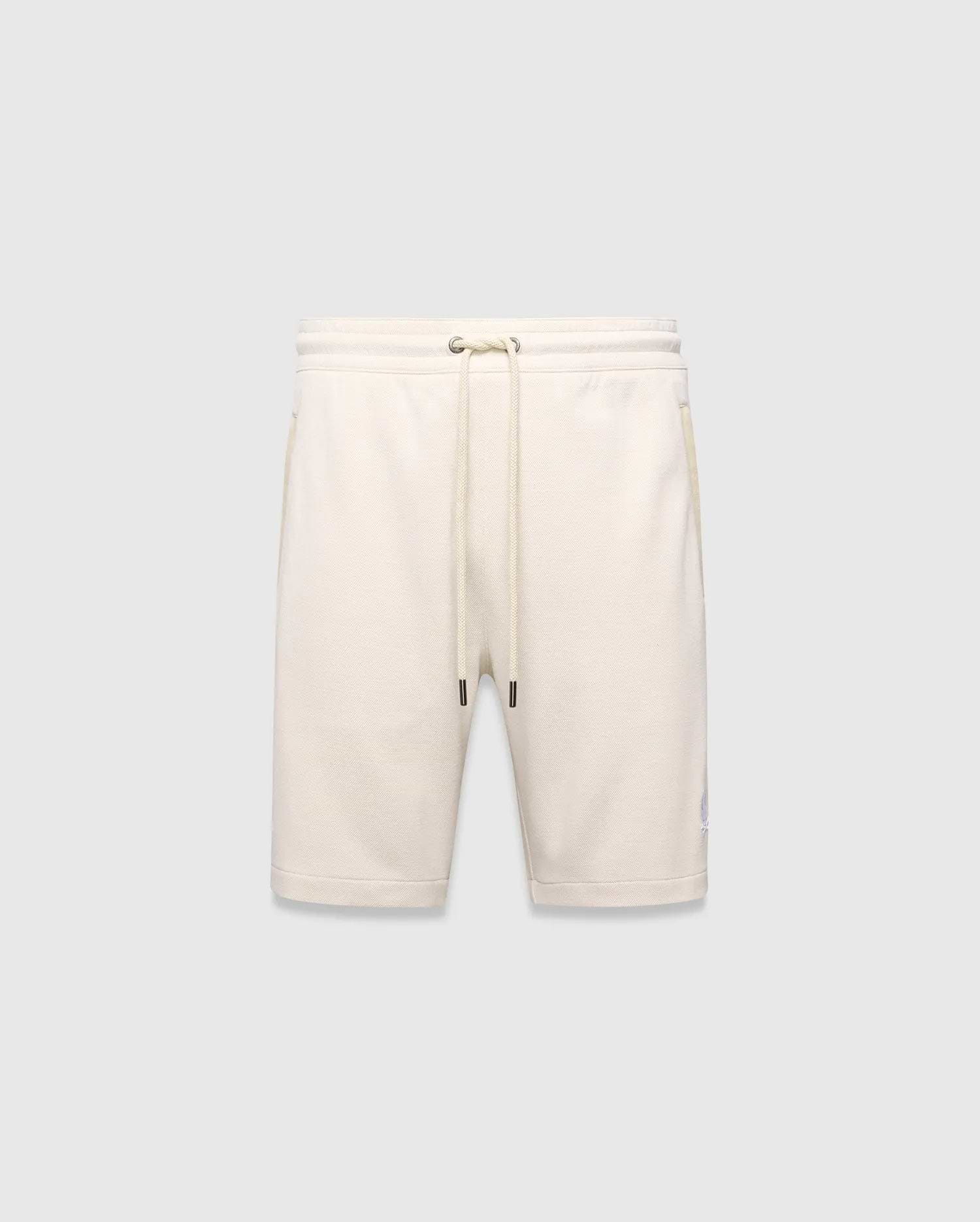 Mens Keith Short 8, cream pique knit shorts with a relaxed fit, featuring a drawstring waist, side pockets, and a small embroidered lavender Psycho Bunny skull logo on the left leg.
