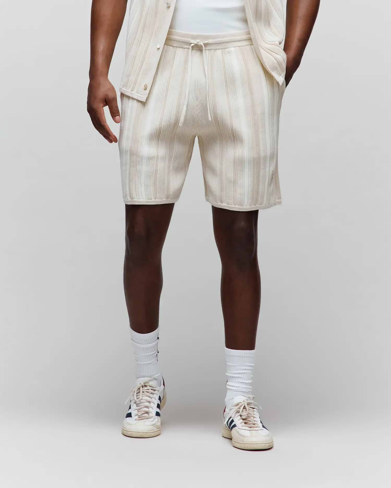 Mens Cliff Knit Short, cream relaxed-fit shorts featuring subtle light brown vertical stripes, a ribbed knit texture, drawstring waist, and a small embroidered Psycho Bunny skull logo on the lower left leg.