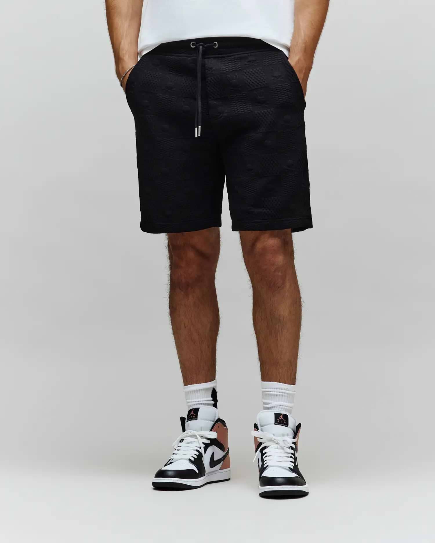 Mens Dustin Sweatshort in black, featuring a relaxed fit and an all-over embossed Psycho Bunny skull pattern, complete with a black drawstring and silver tips.