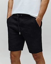 Mens Dustin Sweatshort, black embossed knit fabric with an all-over Psycho Bunny skull logo pattern, relaxed fit, and drawstring waist with silver aglets.