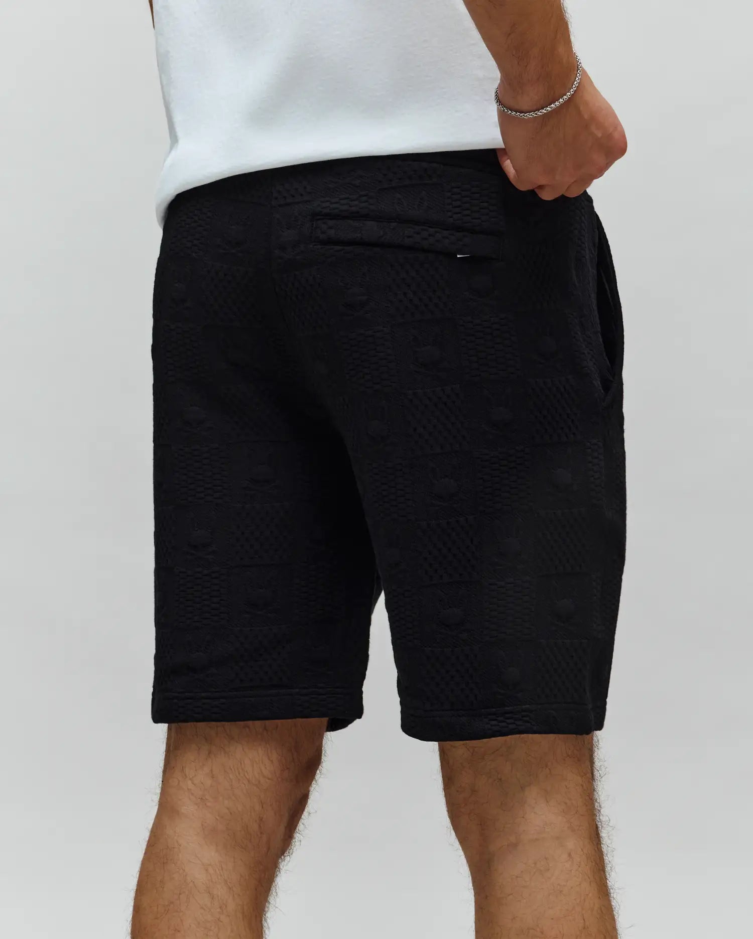 Mens Dustin Sweatshort, black textured knit with all-over embossed bunny skull logo pattern, relaxed fit, featuring a back pocket with a small Psycho Bunny tag.