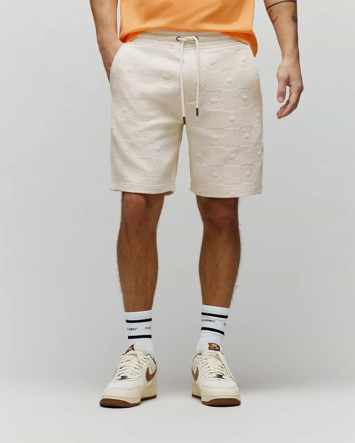 Cream relaxed fit textured knit Mens Dustin Sweatshort with an all-over embossed Psycho Bunny skull logo and checkered pattern, featuring a drawstring waist.
