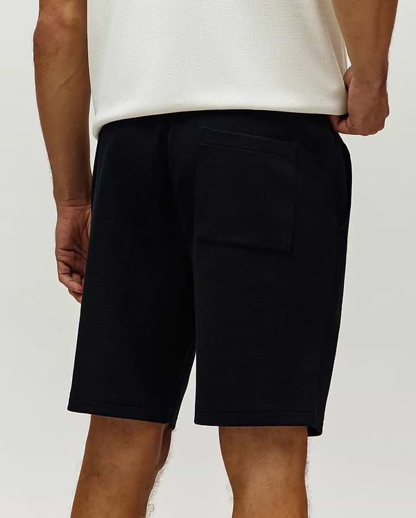 Black Mens Maxton Waffle Sweatshort, a relaxed fit streetwear style, featuring a textured waffle knit fabric, side pockets, and a back patch pocket.