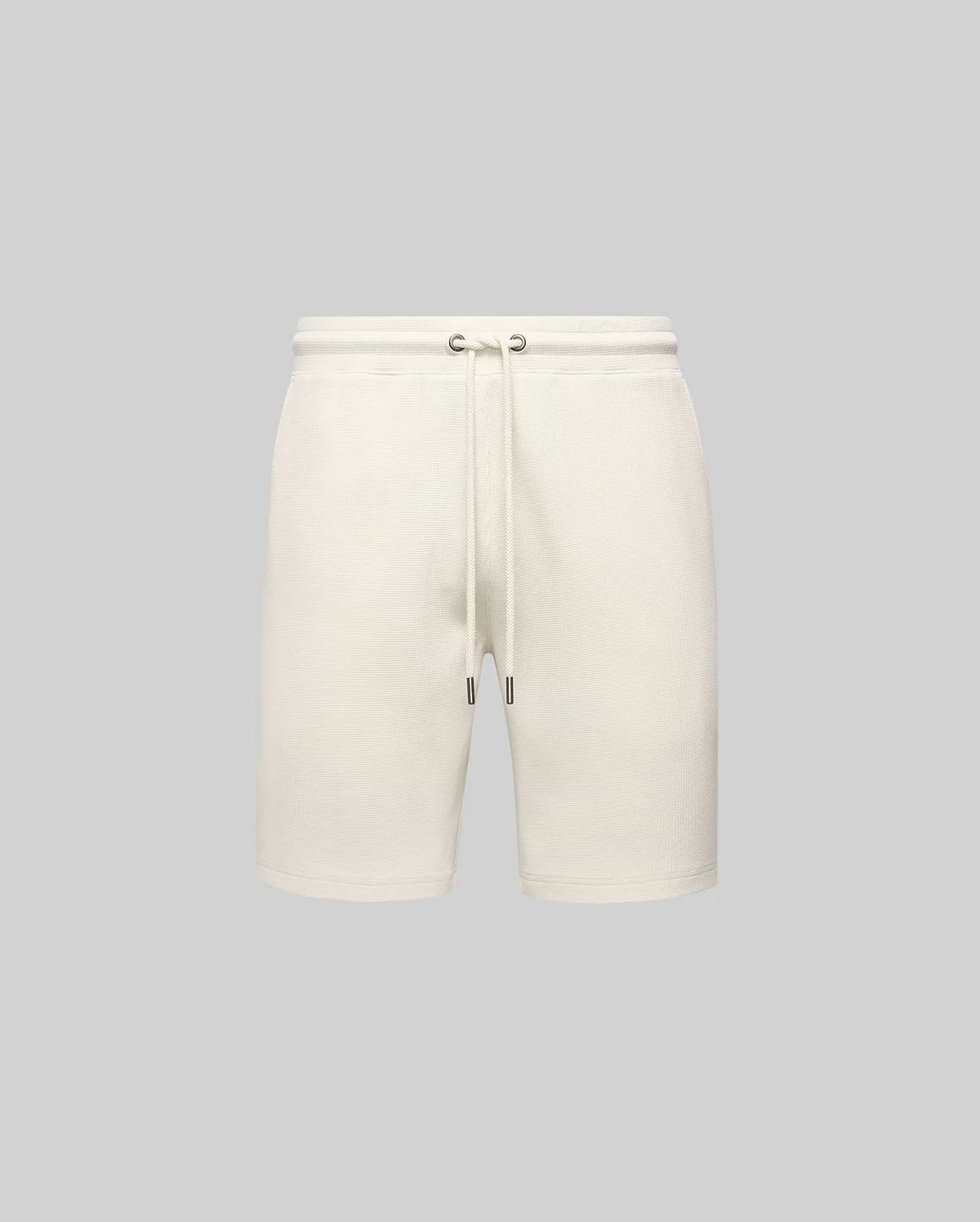 Mens Maxton Waffle Sweatshort in cream, a relaxed fit garment with textured waffle knit fabric, featuring an elastic drawstring waist, metal eyelets, and dark tips. No visible Psycho Bunny logo.