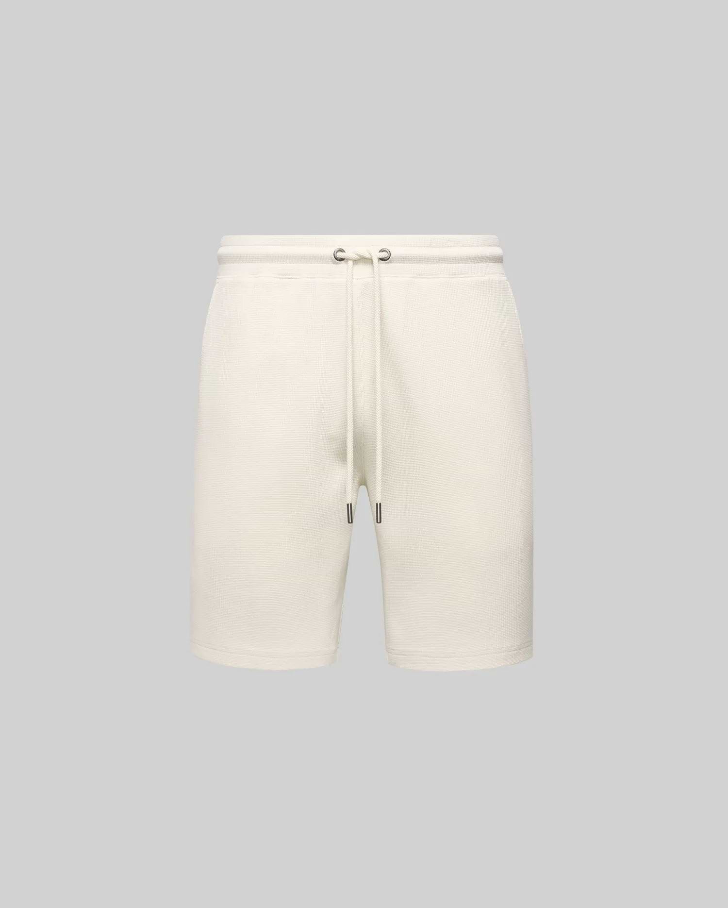 Mens Maxton Waffle Sweatshort in cream, a relaxed fit garment with textured waffle knit fabric, featuring an elastic drawstring waist, metal eyelets, and dark tips. No visible Psycho Bunny logo.