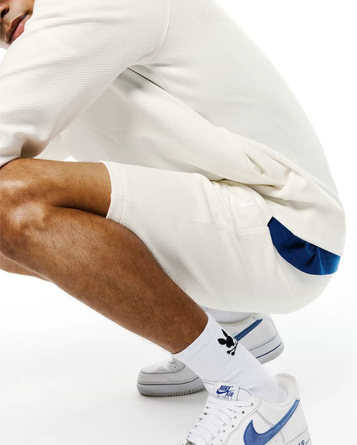 Cream Mens Marc Textured Short with a relaxed fit, featuring a subtle waffle knit texture and a small, tonal embroidered Psycho Bunny skull logo on the left thigh, with a blue accent visible underneath.