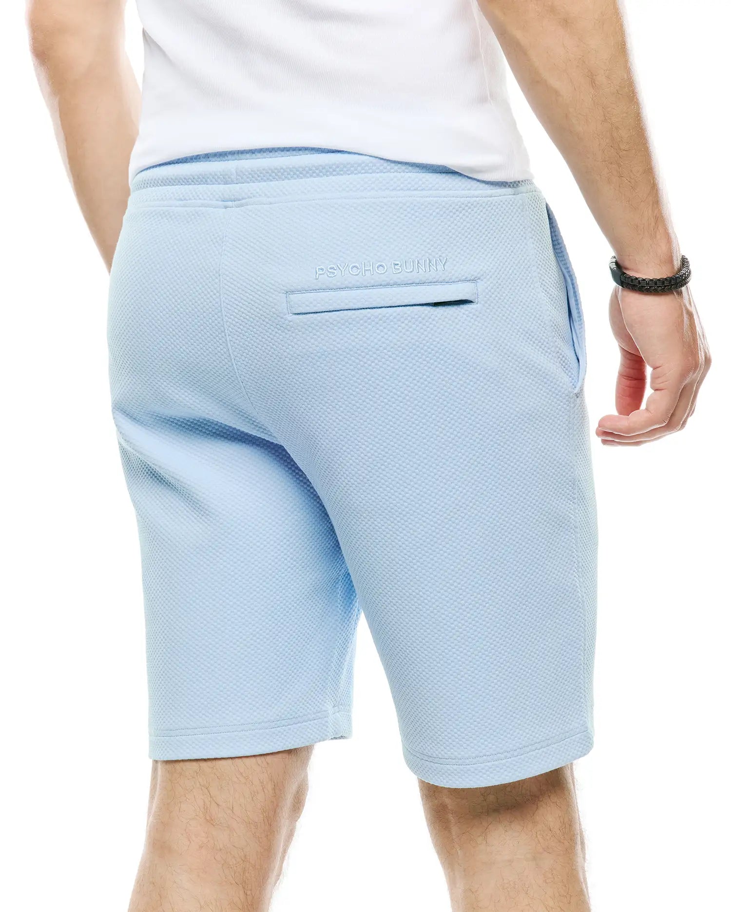 Mens Marc Textured Short in light blue, featuring a relaxed fit, all-over pique texture, and small embroidered Psycho Bunny text above the back welt pocket.