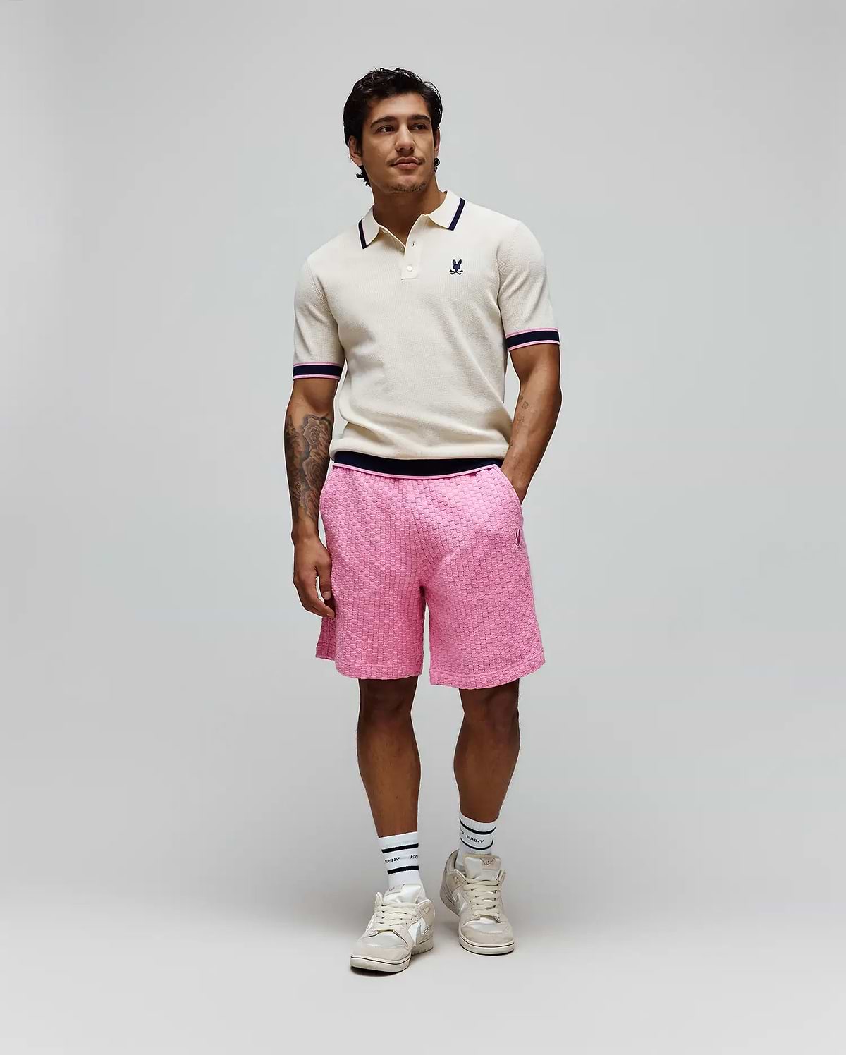 Cream knit polo with navy and pink striped collar/cuffs and embroidered Psycho Bunny logo, paired with bright pink textured knit Mens Garen Knit Short featuring a navy waistband and small bunny skull logo. (3)