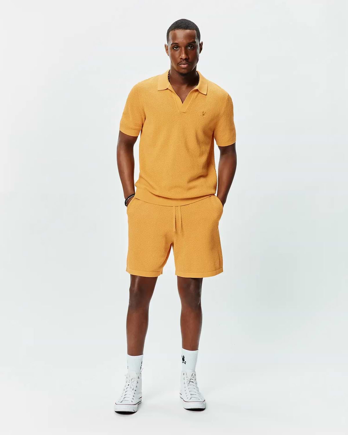 Mustard yellow textured knit polo with V-neck and small embroidered Psycho Bunny logo on left chest, paired with matching Mens Devon Knit Short with drawstring waist.