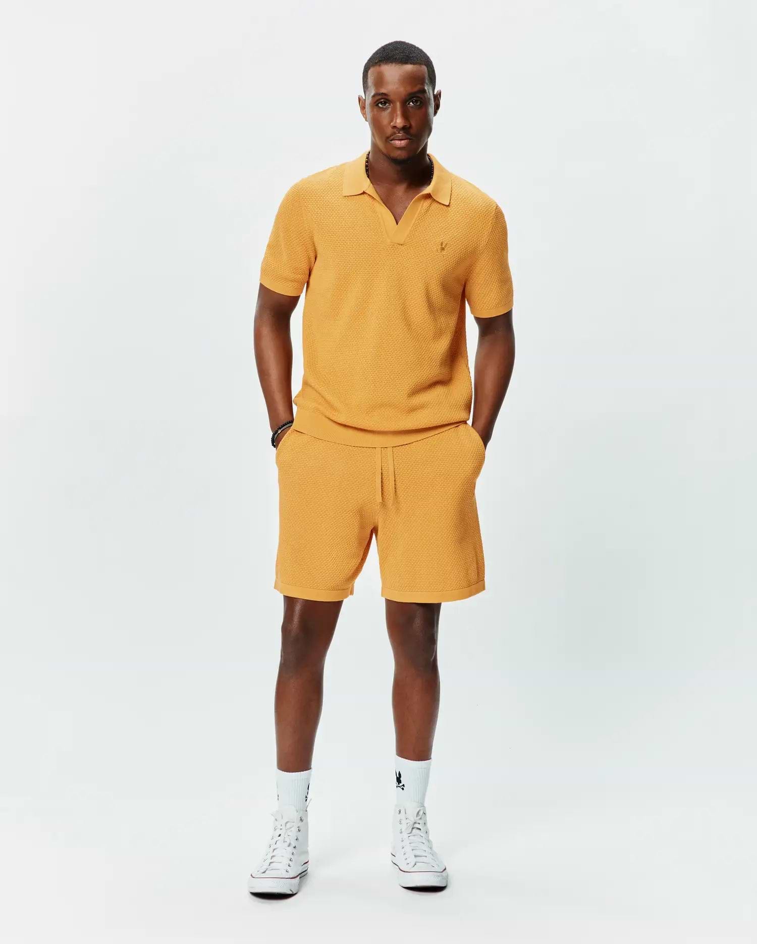 Mustard yellow textured knit polo with V-neck and small embroidered Psycho Bunny logo on left chest, paired with matching Mens Devon Knit Short with drawstring waist.