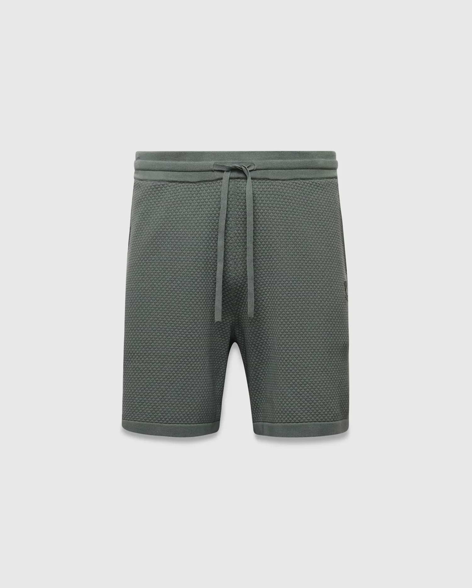 Mens Devon Knit Short 7, a sage green relaxed fit pique knit short with a drawstring waist, ribbed waistband, and a small embroidered Psycho Bunny skull logo on the right thigh.