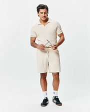 Cream Mens Devon Knit Polo, featuring a classic fit, textured waffle knit fabric, open resort collar, and a small embroidered Psycho Bunny skull logo on the left chest, complemented by matching knit shorts.