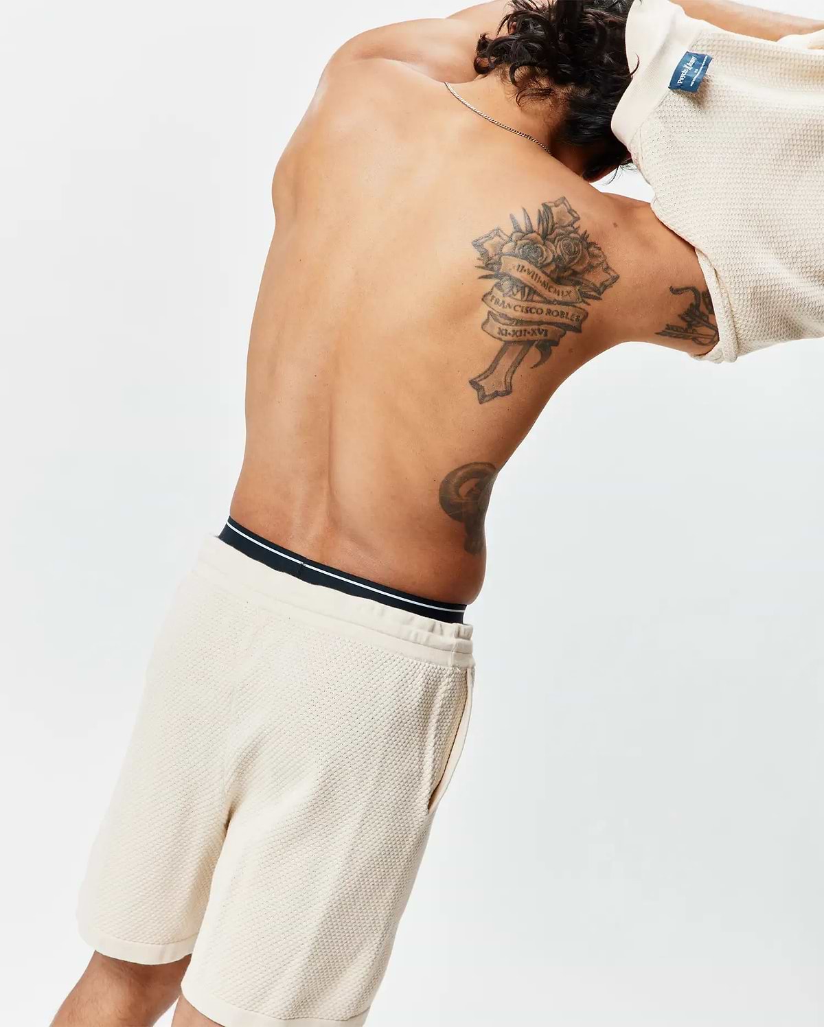 Cream Mens Devon Knit Short, a relaxed waffle knit short with a black and white striped waistband, paired with a matching cream waffle knit top featuring a blue Psycho Bunny tag at the back collar.