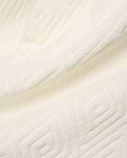 Creamy white Mens Tristan Short crafted from plush, absorbent terry cloth, featuring an intricate, subtly embossed geometric square and spiral pattern throughout the luxurious fabric.