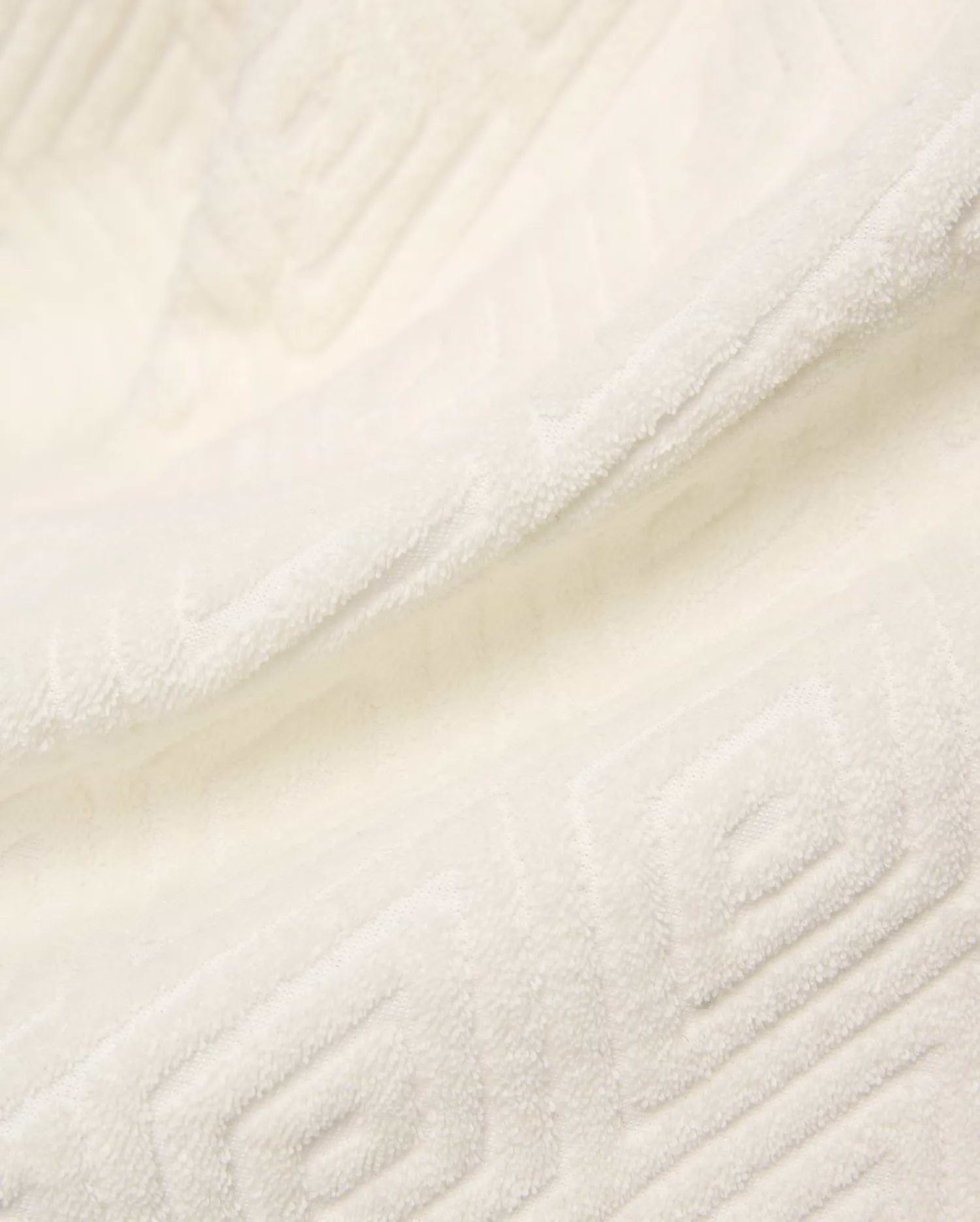 Creamy white Mens Tristan Short crafted from plush, absorbent terry cloth, featuring an intricate, subtly embossed geometric square and spiral pattern throughout the luxurious fabric.