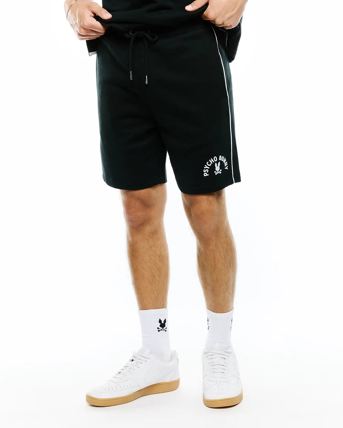 Mens Stevie Short, dark green relaxed fit jersey shorts featuring a white vertical side stripe, drawstring waist, and a medium white Psycho Bunny skull logo on the left thigh.