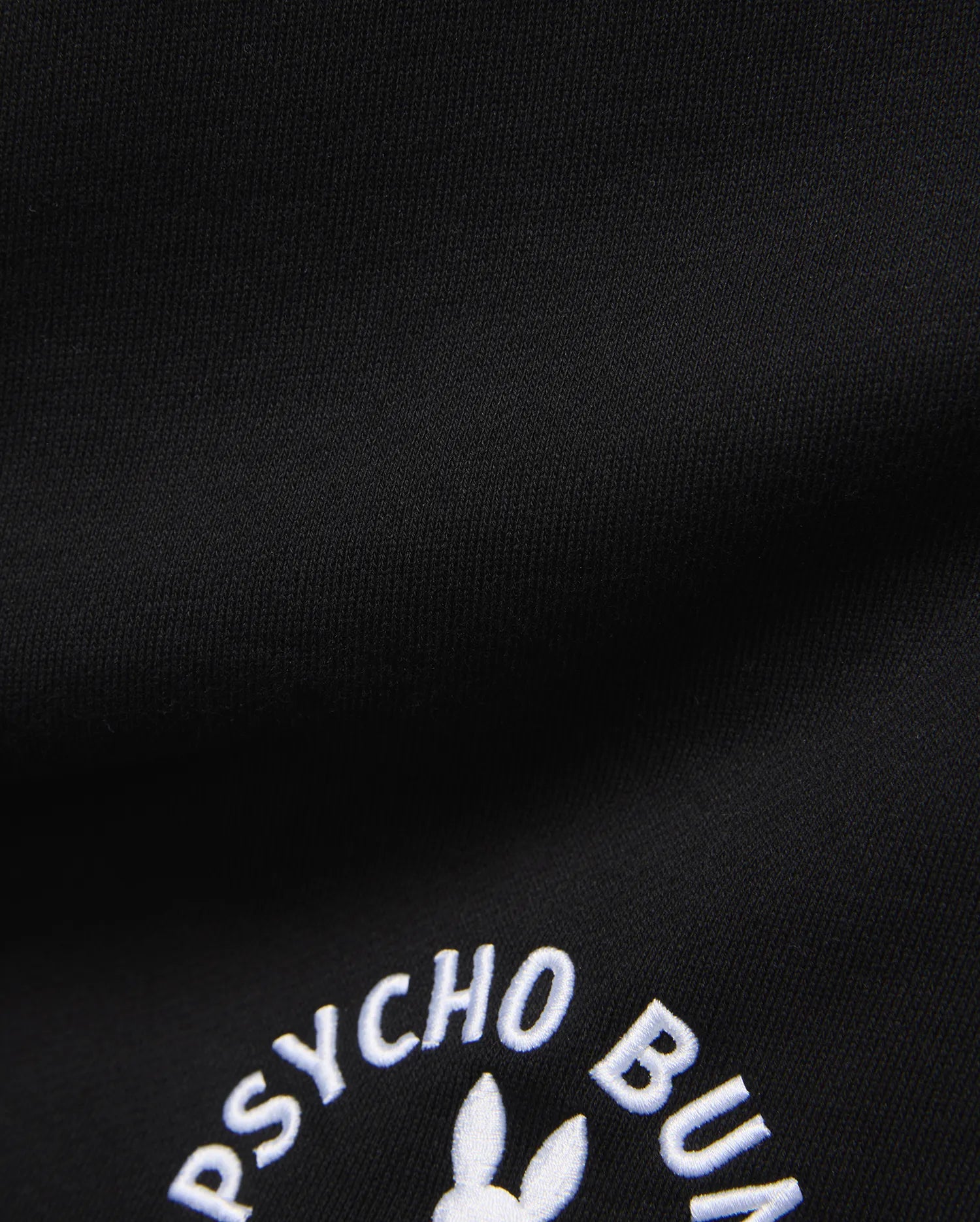 Mens Stevie Short in black, crafted from a smooth, dense knit fabric, prominently featuring the iconic white embroidered Psycho Bunny text and partial bunny skull logo.