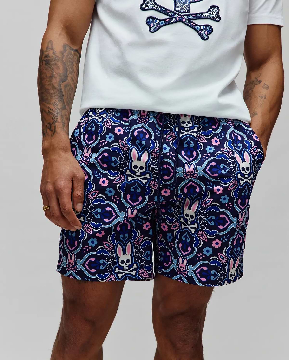 Mens Luke Swim Trunk in navy with an allover intricate floral and paisley pattern featuring repeated pink, light blue, and white Psycho Bunny skull logos, classic fit, smooth quick-dry fabric.