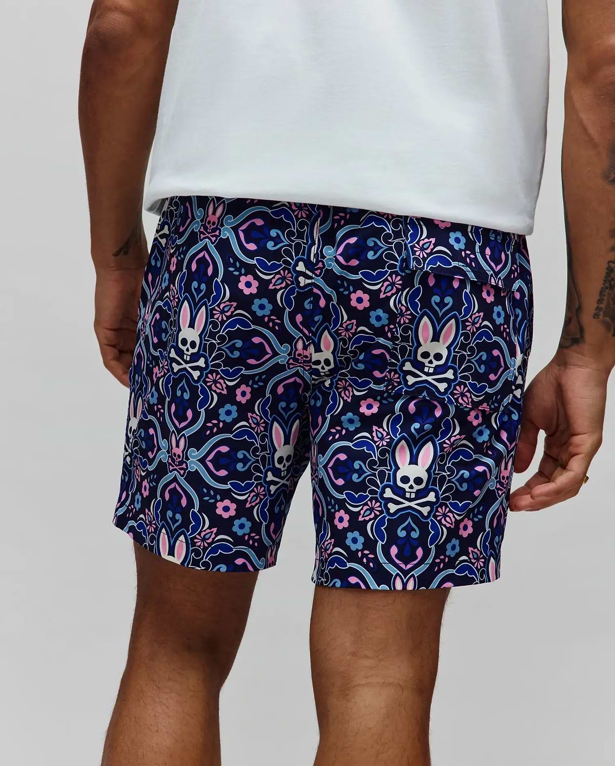Mens Luke Swim Trunk in navy blue with an all-over ornate floral and paisley pattern featuring repeated Psycho Bunny skull logos with pink ears, crafted from smooth, quick-dry fabric in a classic fit.