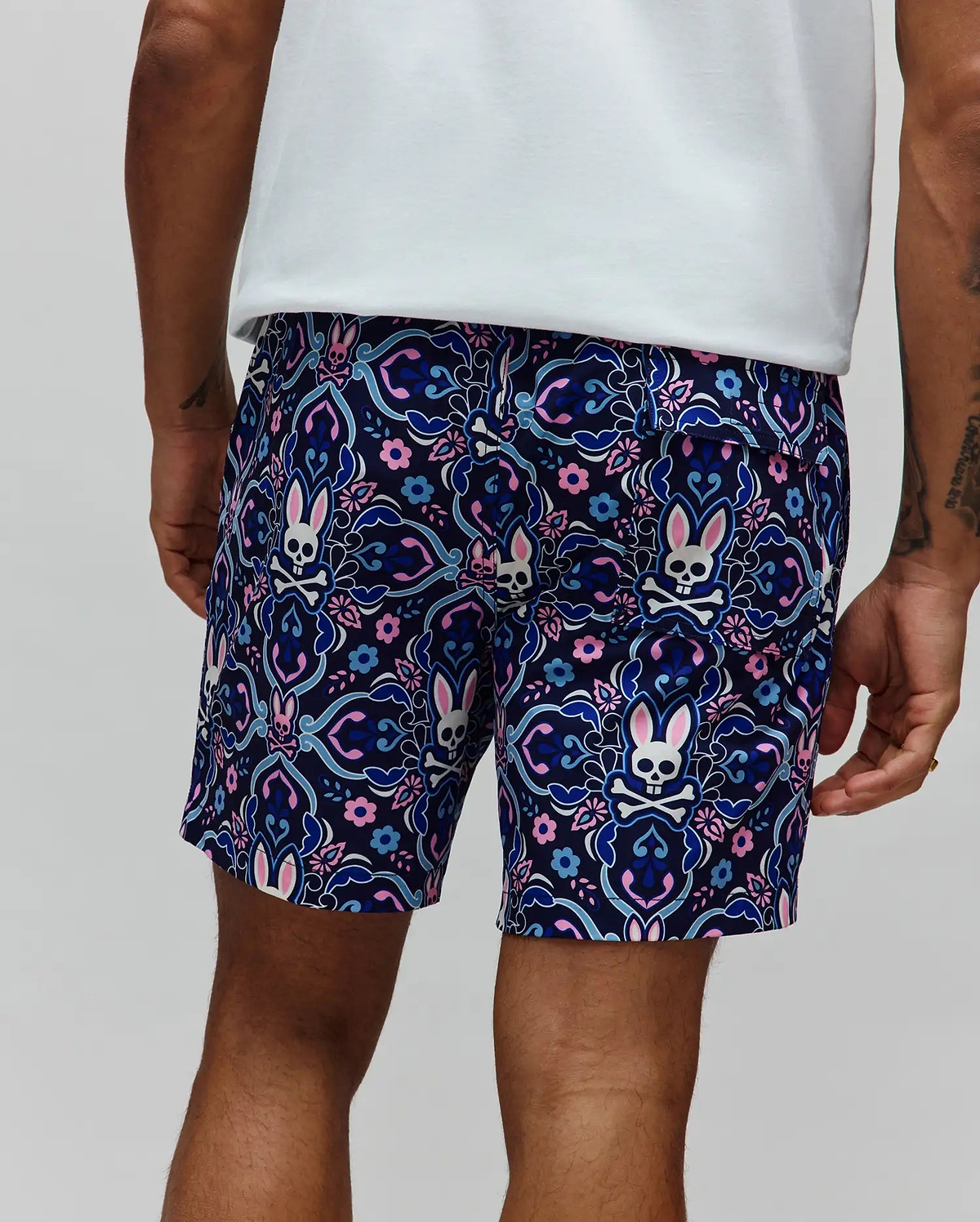 Mens Luke Swim Trunk in navy blue with an all-over ornate floral and paisley pattern featuring repeated Psycho Bunny skull logos with pink ears, crafted from smooth, quick-dry fabric in a classic fit.