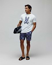 White classic fit jersey t-shirt with a large, colorful paisley Psycho Bunny skull logo on the chest, and Mens Luke Swim Trunk in navy with an all-over intricate pattern featuring small bunny skulls.