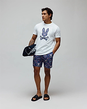 White classic fit jersey t-shirt with a large, colorful paisley Psycho Bunny skull logo on the chest, and Mens Luke Swim Trunk in navy with an all-over intricate pattern featuring small bunny skulls.