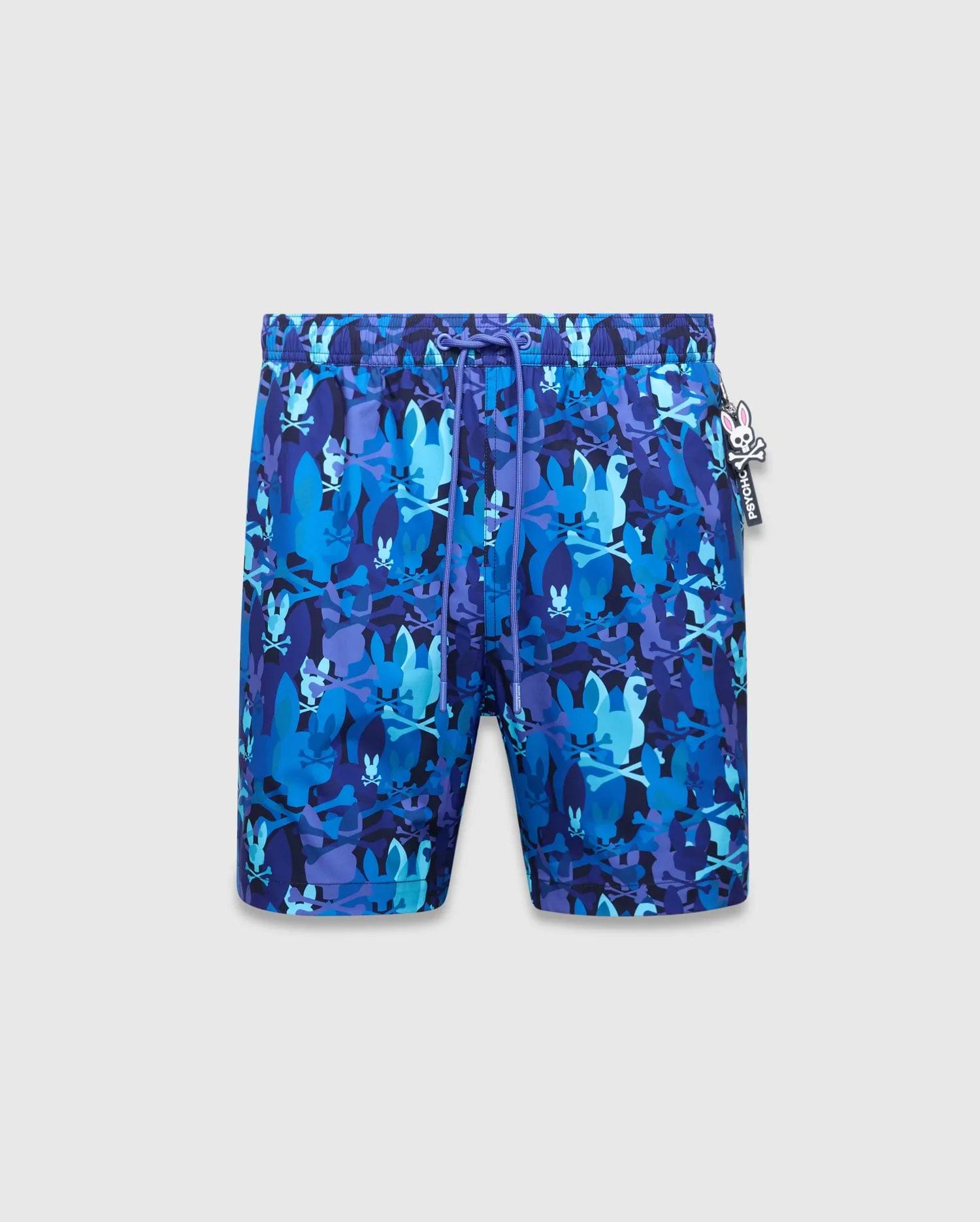Mens Tanner Swim Trunk in a vibrant blue and purple camouflage print, featuring the iconic Psycho Bunny skull and crossbones. This classic fit swim trunk is made from smooth, quick-dry fabric, complete with a drawstring waist and a small Psycho Bunny logo charm.